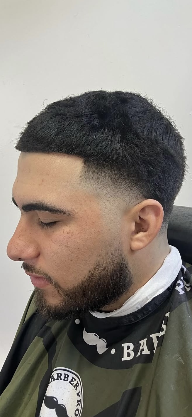 Low taper fade with textured top and beard lineup by Sharp Society Barbershop